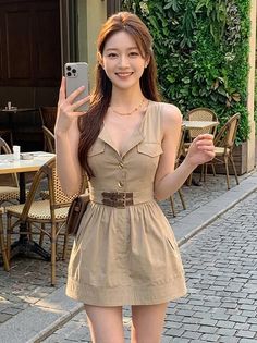 Woman in a sleeveless dress with a brown belt standing on a cobblestone street