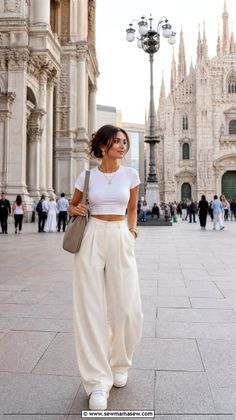 Woman in a white crop top and wide leg pants walking in a city square