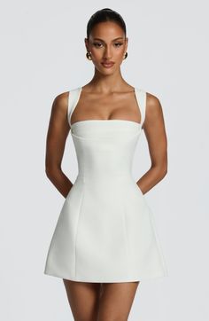 Woman in a white dress with gold earrings posing in a studio