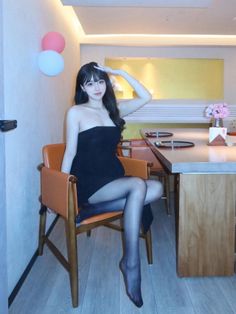 Woman in a black strapless dress and pantyhose sitting indoors