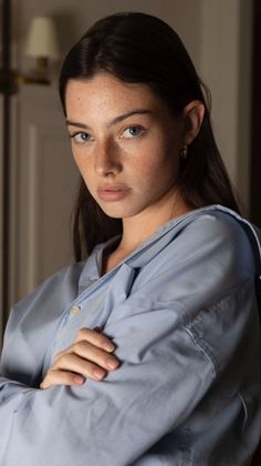 Woman with long dark hair and freckles wearing a blue shirt indoors