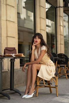Woman in a polka dot dress sitting at an outdoor cafe table