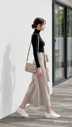 Woman in a black turtleneck and beige wide-leg pants walking outdoors