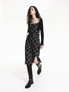 Woman in a plaid dress and black boots on a white background