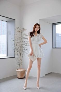 Woman in a white dress and high heels posing indoors
