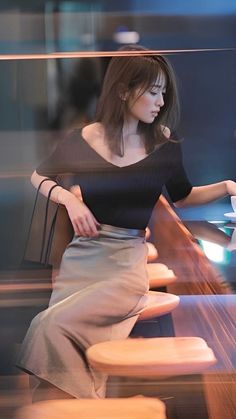 Woman with long hair in a black top and midi skirt, captured with motion blur