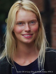 Blonde woman with blue eyes smiling outdoors
