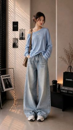 Woman in a light blue off-shoulder top and loose jeans indoors