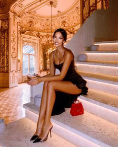 Woman in a black dress and high heels sitting on a grand staircase