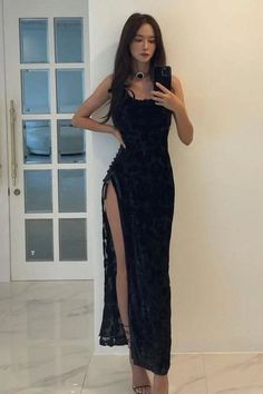 Woman in a black dress with a high slit taking a mirror selfie