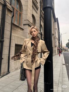 Woman in a trench coat and leopard print scarf on a city street