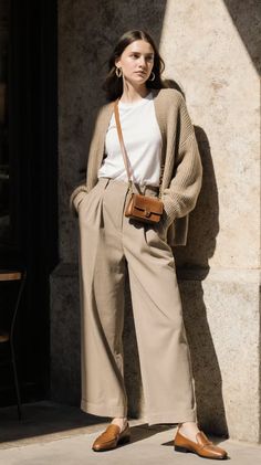 Woman in a cardigan and wide leg pants standing outdoors with dramatic lighting
