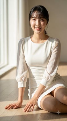 Woman in a white dress sitting on a wooden floor with natural light