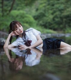 Woman in a school uniform lying in shallow water with a reflection