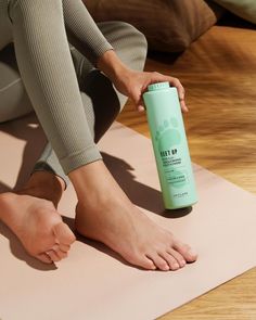 Person holding foot powder with bare feet on a yoga mat