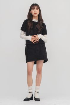 Woman in a black fuzzy top and skirt with white long sleeves and socks