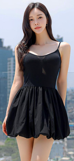 Woman in a black dress with long hair outdoors against a cityscape