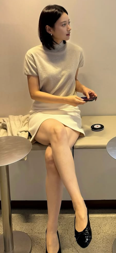 Woman with short hair and a mini skirt sitting indoors