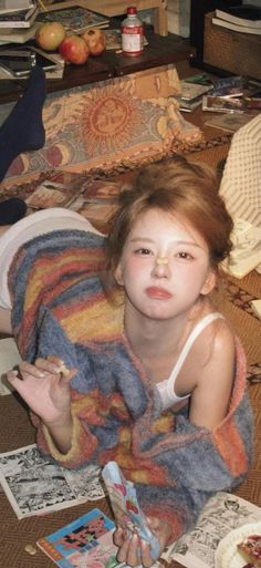 Woman with a messy bun and striped sweater lying on a cluttered floor
