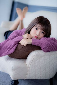 Woman in a purple sweater lying on a couch with bare feet