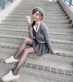 Woman in a gray beret and sweater sitting on outdoor stairs