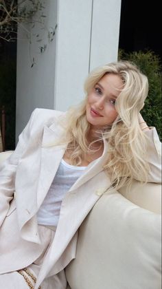 Woman with blonde hair wearing a white blazer and tank top outdoors