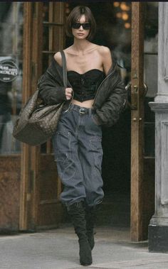 Woman in a black corset, cargo pants, and bomber jacket walking outdoors