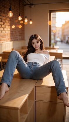 Woman in an off-shoulder top and jeans posing on a wooden counter indoors