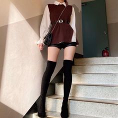 Person in a white shirt, brown vest, leather shorts, and thigh high boots on stairs