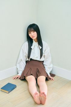 Young woman with long black hair sitting on the floor with a book