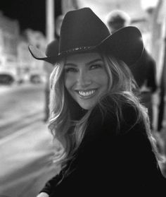 Woman in a cowboy hat smiling in a black and white outdoor portrait