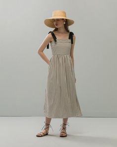 Woman in a striped dress and straw hat posing in a studio