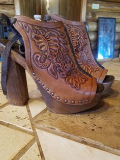 Pair of brown leather platform shoes with carved floral designs and wooden heels