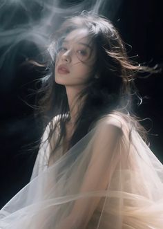 Woman with long hair and sheer fabric against a dark background