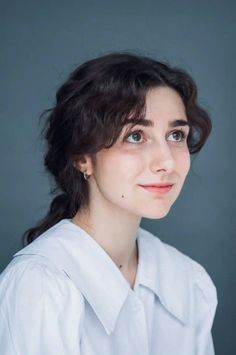 Woman with dark, curly hair wearing a white shirt and hoop earrings