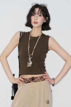 Woman with short hair and sunglasses on her head, wearing a sleeveless top and plaid waistband