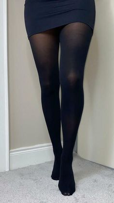 Person wearing black tights and a short skirt standing on a light carpet