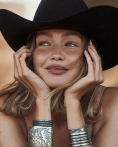 Woman in a cowboy hat with freckles and silver bracelets, looking up