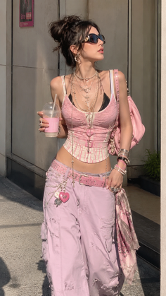 Woman in a pink crop top and cargo pants with layered necklaces and sunglasses