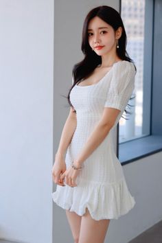 Woman in a white dress with long dark hair posing indoors