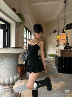 Woman in a black dress and long boots posing indoors