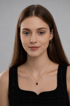 Woman with long brown hair wearing a black top and gold jewelry