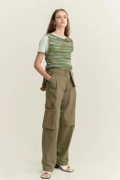 Woman in a knitted vest and cargo pants with hoop earrings in a studio