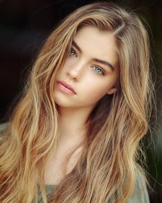 Young woman with long blonde hair and blue eyes in a soft-lit portrait