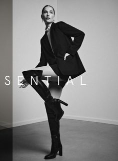 Woman in a suit jacket and thigh-high boots posing indoors