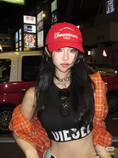 Woman in a red baseball cap and crop top on a city street at night