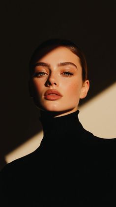 Woman in a black turtleneck with dramatic lighting on her face