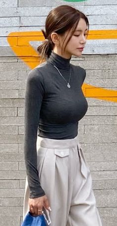 Woman in a dark turtleneck and light wide leg pants outdoors
