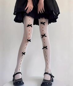 Person wearing white tights with black bows and a black dress