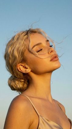 Woman with blonde hair in an updo, bathed in golden hour light outdoors